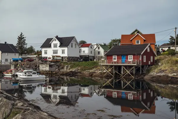 Henningsvr 'deki pitoresk bir liman köyünde, Norveç' in Lofoten Adaları 'ndaki alacakaranlıkta sakin sularda güzel yansıyan kırmızı kulübeler ve tekneler sergilenmektedir.