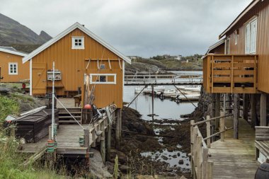 Renkli kulübeler Norveç 'teki Lofoten Adaları' nın sularını kaplayarak pitoresk bir kış manzarası yaratır. Bulutlar havada süzülürken balıkçı tekneleri huzur içinde dinleniyor..