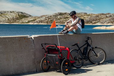 Bodo, Norveç - 12 Ağustos 2018: Dövmeli adam Bodo, Lofoten 'de okyanusta bisiklet ve bebek arabasıyla rahatlıyor