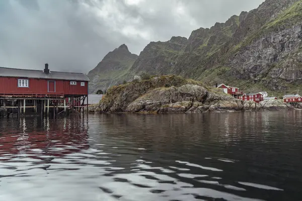 Görkemli dağların arka planına kurulmuş, kıyıdaki geleneksel kırmızı kulübeler, Lofoten Adaları 'nın sakin sularına yansıyarak turistler için mükemmel bir kaçış sağlar..