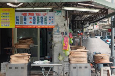 Taipei 'de, hareketli bir sokak yemeği tezgahında bambu sepetleri dolusu hamur tatlısı pişiriliyor. Taze yiyecek kokusu havayı doldururken renkli işaretler müşterileri çeker..