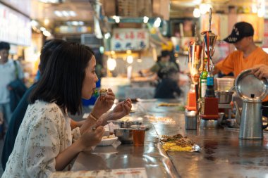 Taipei, Taiwan - October 10th 2019: Enjoying a delightful meal at a bustling night market in Taipei, Taiwan during the evening hours clipart