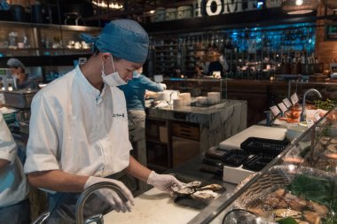 Taipei, Tayvan - 10 Ekim 2019: Yetenekli bir şef yemek servisi sırasında kalabalık bir Taipei restoranında taze istiridye hazırlıyor