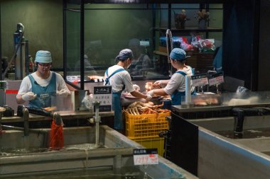 Taipei, Taiwan - October 10th 2019: Artisan fishmongers at work in a bustling Taipei seafood market during a vibrant morning clipart