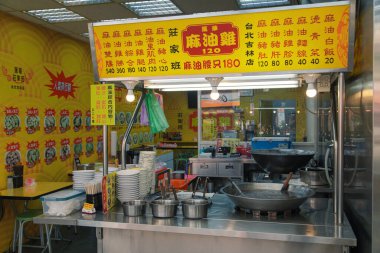 A vibrant street food stall in Taipei offers a variety of freshly prepared meals. Bright yellow signage displays menu items, while cooking equipment and utensils are ready for service.