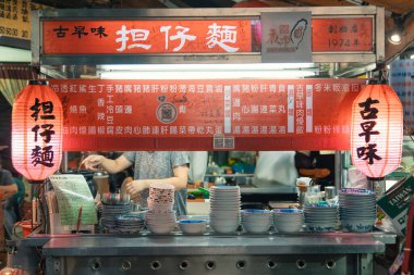Taipei 'deki hareketli bir sokak yemekhanesinde renkli geleneksel şehriyeler sergileniyor. Fenerler tezgahı aydınlatarak yerel lezzetleri tatmak isteyen aç müşterileri cezbediyor..