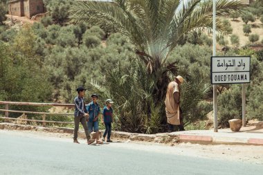Kırsal bölge, Fas, 23 Temmuz 2019: Fas yolunda palmiye ağaçları ve yerel tabelalarla gezen aileler