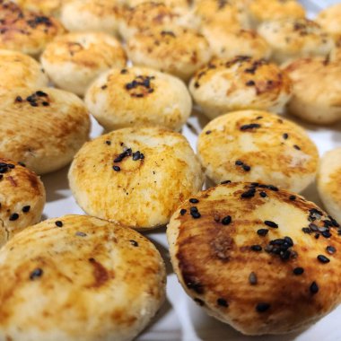 Siyah susam tohumlarıyla kaplı küçük parti atıştırmalıkları ve beyaz seramik tepside fırında pişirilmiş. 