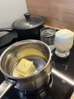 Tereyağı, bir bardak su ve un ile birlikte sobanın tepesinde eriyor. Bu da lezzetli bir tatlıya hazırlanan turta kabuğunun başlangıcını gösteriyor..