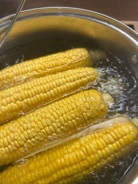 Koçandaki çıtır çıtır sarı mısır, sıcak bir öğleden sonra sıcak bir ev mutfağında buhar yaratarak sobanın üstünde bir tencere suda kaynatılıyor. Aşçılığın kokusu havayı dolduruyor..