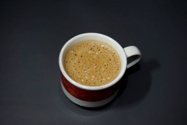 Köpüklü, taze demlenmiş kahveyle dolu bir bardağın yakın plan fotoğrafı..