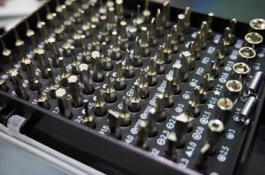 Farklı boyutlarda ve tiplerde çeşitli hassas tornavidalarla dolu bir siyah düzenleyici kutusunun yüksek çözünürlüklü yakın çekimi.