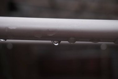 Beyaz metal korkuluklara tutunan su damlacıklarının yakın çekim görüntüsü..