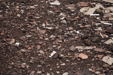 Kırık kiremitler, tuğla parçaları, odun kalıntıları, kömür ve küçük kayalarla dolu zemin yüzeyinin yüksek açılı yakın çekim görüntüsü..