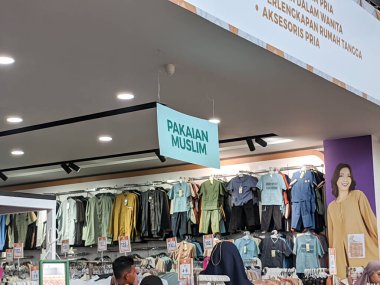 Parlak ışıklandırılmış bir perakende mağazasında askılarda geniş bir dizi Müslüman kıyafeti sergileniyor..