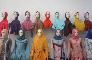 Mankenler üzerinde çeşitli renkli ve şık başörtüleri ve mütevazı giysiler sergilenir..