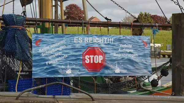 Greetsiel, Almanya - 24 Mayıs 2023: Greetsiel Limanı 'nda bir pankart, planlanan alt trol teknesi yasağını protesto ediyor. Balıkçılar sanayilerinin sonundan korkuyorlar.