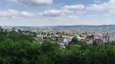 Yüksek Angle Pan, Wuppertal Oberbarmen 'e karşı, parktaki parktaki barmen, güneş ışığı, mavi gökyüzü ve güzel bulutlarla.