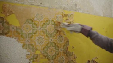 Bir Eldiven ve Kazıyıcı eski bir duvar kağıdını yeni duvar kağıdı ya da boyaya hazırlıyor. Eski boyaları ortaya çıkarmak.