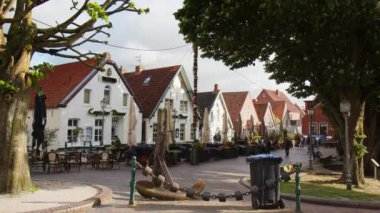 Selamlar, Almanya - 24 Mayıs 2023: Greetsiel 'de Idyllic Street Am Markt, Kuzey Frizya' da küçük resimli bir balıkçı kasabası. Bazı turistler yaz sezonu başlamadan önce etrafta dolaşıyorlar. Eski çapa