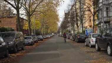 BERLİN, GERMANY - NOVEMBER 10, 2021: Kreuzberg 'deki Bergmanstrasse boyunca bisiklet süren bisikletçi daha sonra güneşli bir sonbahar gününde Bisiklet Caddesi Fahrradstrasse' nin Alman tabelasına eğildi. Sol taraftaki mezarlıkta..