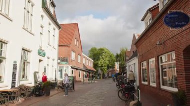 Selamlar, Almanya - 24 Mayıs 2023: Greetsiel 'de küçük dükkanları olan küçük bir sokak, Kuzey Frizya' da küçük pitoresk bir balıkçı kasabası. Bazı turistler yaz sezonu başlamadan önce etrafta dolaşıyorlar. 