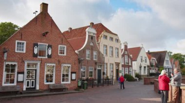 Selamlar, Almanya - 24 Mayıs 2023: Greetsiel 'deki Idyllic eski evler, Kuzey Frizya' da küçük pitoresk bir balıkçı kasabası. Bazı turistler yaz sezonu başlamadan önce etrafta dolaşıyorlar. Sielstrasse ve