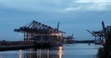 HAMBURG, 2013: Güneş Hamburg limanında büyük Gantry Turnaları (Konteyner Turnaları) ile batarken konteynırlar bir konteyner gemisinden indiriliyor.