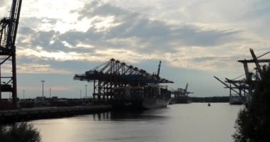 HAMBURG, 2013: Güneş Hamburg limanında büyük Gantry Turnaları (Konteyner Turnaları) ile batarken konteynırlar bir konteyner gemisinden indiriliyor.