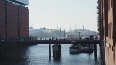 HAMBURG, GERMANY - 27 Mart 2022: güneşli bir günde Elbe Filarmoni Salonu 'ndaki Kaiserkai Köprüsü' nde yürüyen insanlar. Arka planda Aslan Kral ve Donmuş Müzikal Tiyatro.