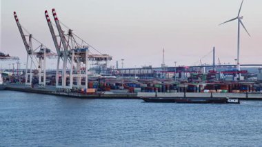 HAMBURG, GERMANY - 19 Mart 2022 Alacakaranlıkta Hamburg Limanı 'nda yüklenen konteynır besleme gemisiyle konteynır gemilerine binmek. Taşınmış konteynırlar 