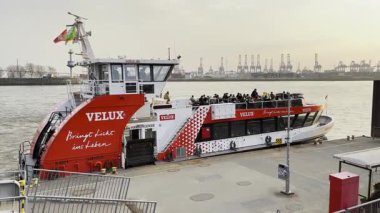 HAMBURG, ALMANY - 24 Mart 2022 'de Hamburg Limanı' ndaki Elbe Nehri 'ndeki rıhtım iskelesinden kalkan feribot yolcuları aldıktan sonra gün batımına doğru yola çıktı. Toplu Taşıma.