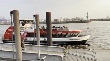 HAMBURG, ALMANY - 24 Mart 2022 Liman Feribotu yolculara binmek için Hamburg Limanı Elbe Nehri 'ndeki rıhtım iskelesi istasyonuna varıyor. Altı feribot hattı toplu taşımanın bir parçası..