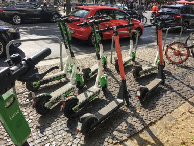 BERLİN - EPTEMBER 08, 2019: Brandenburg Kapısı 'na yakın bir kaldırımda kaotik bir şekilde park etmiş farklı Ride Ride Paylaşımcılık Şirketlerinin birçok elektrikli E-Scooter' ı. Modern ve modaya uygun Şehir Taşımacılığı