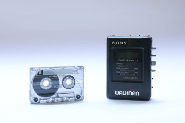 Berlin, Almanya - 3 Mayıs 2025: Vintage Sony Walkman beyaz üzerine bir ses kasetinin yanında. Sony WM-B47, 80 'lerde ve 90' larda popüler bir taşınabilir kasetçaydı..