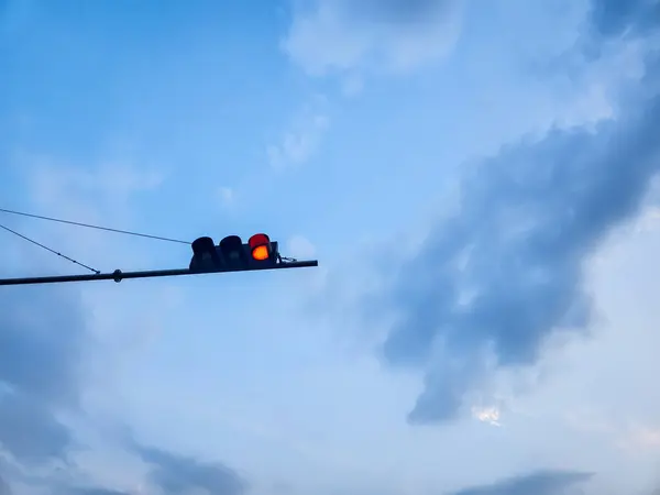 Açık gökyüzü ve beyaz bulutların arka planına karşı kırmızı semafor ışıklarıyla trafik ışığı