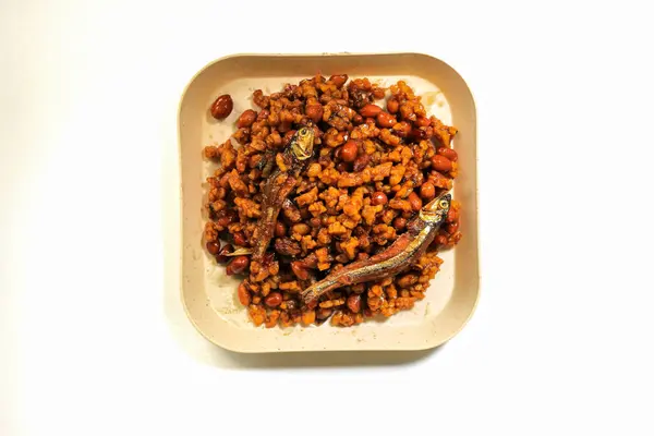 Endonezya yemeği kurutulmuş tempeh, Tempeh ya da soya fasulyesinden yapılır küçük parçalara ayrılır, acı biber, soya sosu ve ançüezle pişirilir, beyaz arka planda izole edilir.