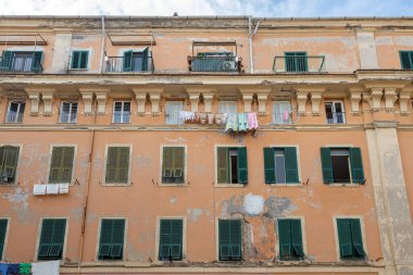 Piazza Leandra, Civitavecchia, İtalya 'da yıpranmış duvarları ve asılı giysileri olan tarihi cephelerin görüntüsü