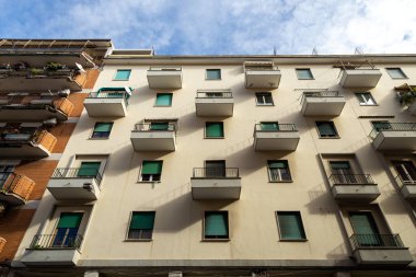 İtalya, Civitavecchia 'da bir apartmanın ön cephesinde, hizalanmış balkonları ve yeşil panjurları var.