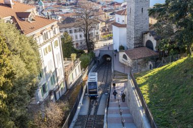 Lugano, İsviçre - 24 Aralık 2024: Bir füniküler Lugano manzaralı kentinde yayaların yanında seyahat ediyor
