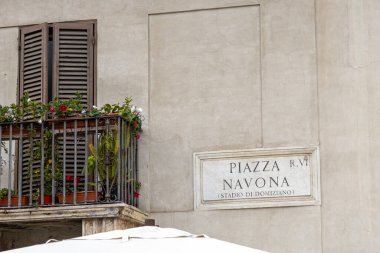İtalya 'nın tarihi şehir merkezinde, Piazza Navona tabelasının yanında çiçeklerle dolu bir balkon.