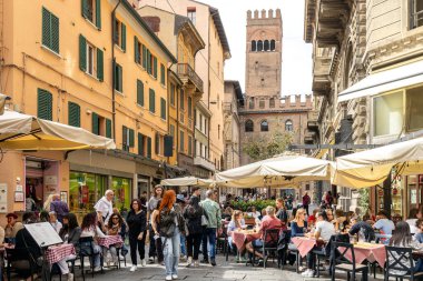 Bologna, Italy - Sep 15th, 2024: Busy street with people enjoying outdoor dining and the Torre dellArengo in the background clipart