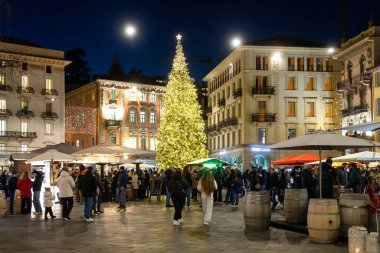 Lugano, İsviçre - 23 Aralık 2024: Piazza della Riforma 'da Noel ağacı, şenlikli süslemeler, insanlar ve gece ışıkları