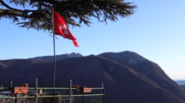 İsviçre bayrağı gün batımında Monte Bre 'de dalgalanırken, arka planda Alpler, Lugano, İsviçre
