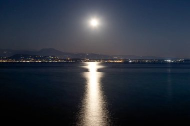 Garda Gölü 'nün üzerinde dolunay, İtalya Sirmione' nin sakin sularına yansıyor.