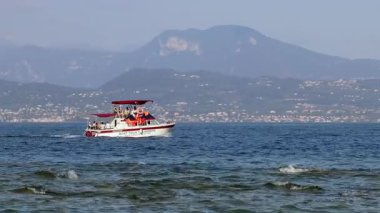 Sirmione, İtalya - 21 Eylül 2024: Turistler Garda Gölü 'nde manzaralı bir dağ manzaralı tekne turunun keyfini çıkarıyorlar