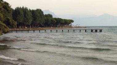 Sirmione, İtalya 'daki Garda Gölü' nün üzerinde iskele, rüzgarlı koşullar ve suda küçük dalgalar.