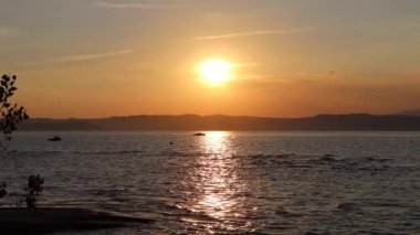 Sirmione, İtalya 'da altın yansımalar ve teknelerle Garda Gölü' nde muhteşem bir gün batımı.