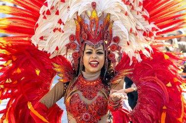 Piove di Sacco, Padua, İtalya - 16 Mart 2025: Karnaval sokak geçit töreni sırasında canlı kırmızı tüy kostümlü gülümseyen Brezilyalı samba dansçısı