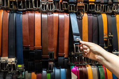 Florence, İtalya - 10 Mayıs 2025 Mercato Nuovo 'daki renkli bir marketten deri kemer seçen bir müşteri.